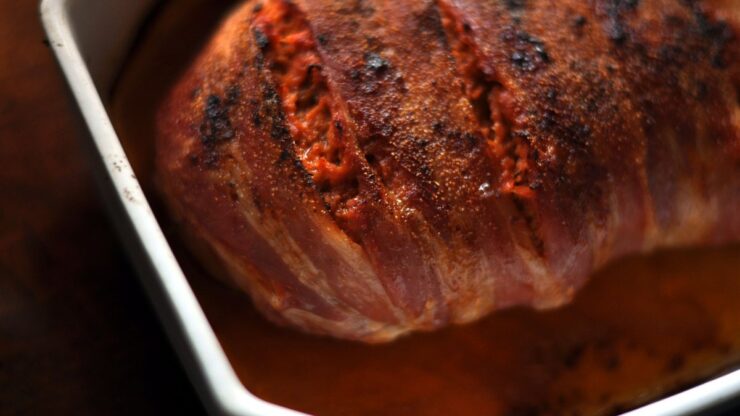 Forloren hare beklædt med sprødstegt bacon i et hvidt ildfast fad