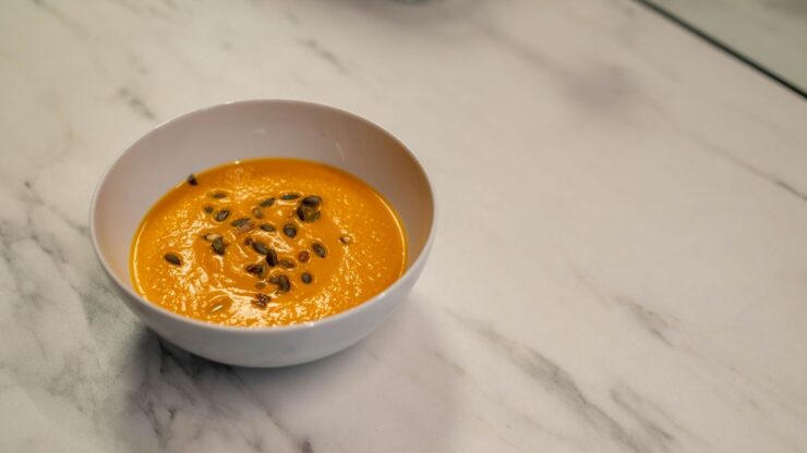 Hokkaido græskarsuppe i hvid skål med græskarkerner