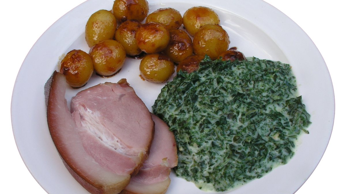 Tallerken med grønlangkål, skiver af kogt hamburgerryg og brunede kartofler